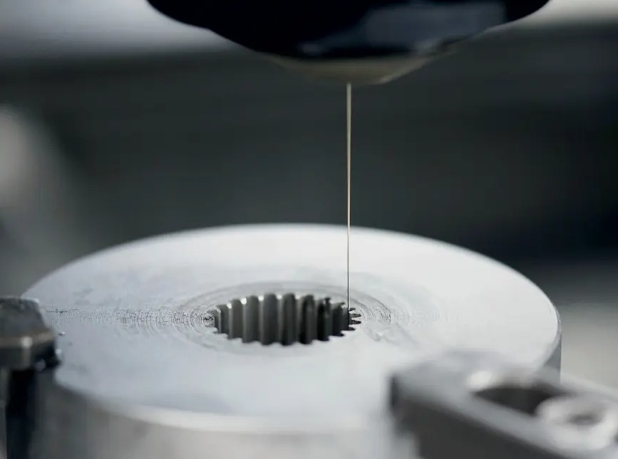 EDM wire threading through a splined metal workpiece in a Mitsubishi wire EDM machine